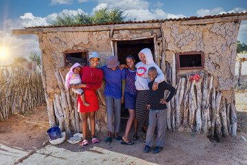 african village, large extended family standing in front of the mud house in the village