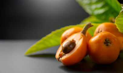 Loquat fruit or Japanese medlars, Nispero, Eriobotrya japonica with leaves fresh ripe bio vegetarian food, medlar berries. Close up. On black table background