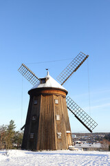 A wooden  smock mill type of  windmill in a winter scene.