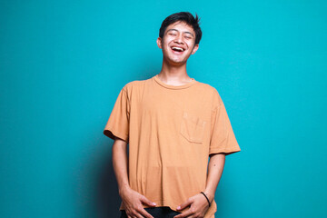 Young man in casual style loudly laughing isolated on blue background