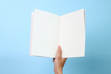 Hands holding a blank book ready with copy space ready for text isolated on blue background