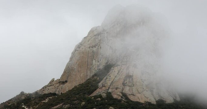 Morning fog envelopes the famous Pe&ntilde;a de Bernal, a mountain peak of Bernal, Quer&eacute;taro, Mexico.
