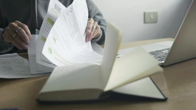 Closeup Slow motion elder caucasian woman hands pass through paper bills office laptop organizer, accounting home payments concept next to laptop