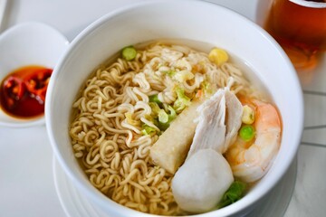A bowl of egg ramen noodles with chicken breast, prawn, bean curd, fish ball and Asian vegetables...