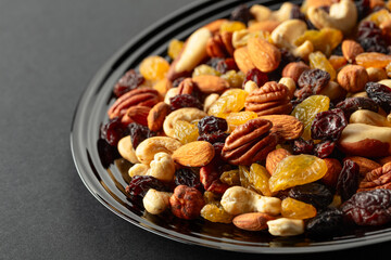 Mix of dried nuts and raisins on a black background.