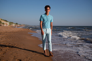 A young attractive guy is walking on the beach.