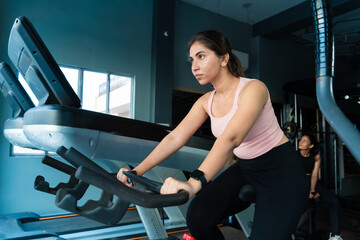Sporty Young fit asian indian adult girl do Cardio exercise cycling at gym. Sport woman workout,...