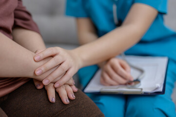 Close-up of a female nurse or therapist holding hands and giving encouragement to an obese Down...
