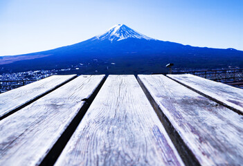 Empty blank wood plank or brown table with Mount Fuji world famous tourist attractions. Abstract Texture background. Beautiful Fuji mountain with snow cover on top with Bright blue sky, bright.