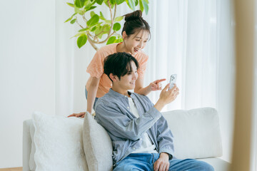 リビングでくつろぎながらスマホを見る若いカップル	