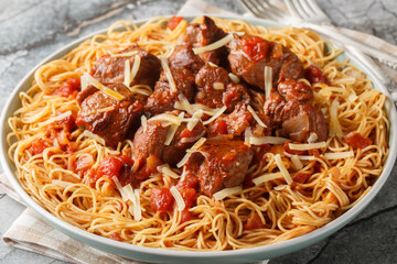 Moshari Kokkinisto or Tas Kebap Greek Veal Stew in a Tomato Sauce with pasta spaghetti closeup on...