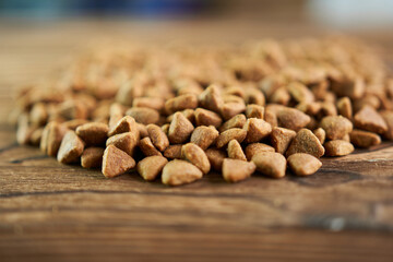 Pile of dry dog food on wooden background. Selective focus.