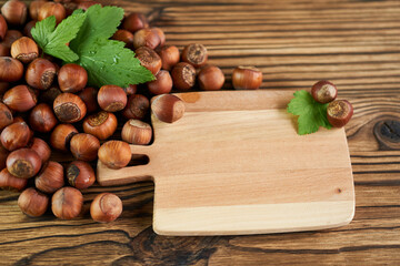 Hazelnuts on a wooden table with a cutting board and leaves