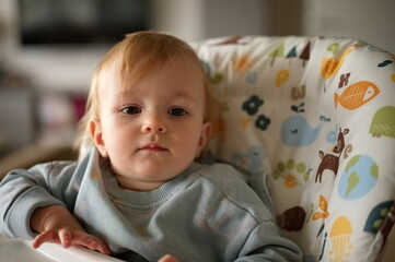 Adorable little baby girl sitting in high chair