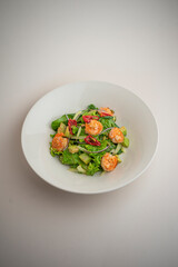 green salad with shrimp and chili pepper on a gray background