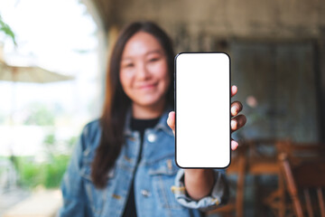 Mockup image of a woman holding and showing a mobile phone with blank white screen - obrazy, fototapety, plakaty