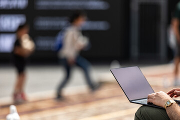 Working Remotely - A man works on his laptop in an urban outdoor setting
