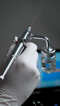 Professional female cosmetologist perform a hydrafacial procedure in modern a cosmetology clinic with airbrush
