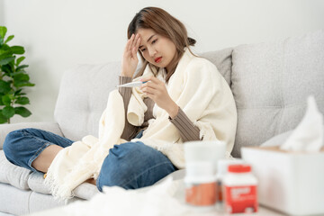 Young Asian woman having high fever while checking body temperature, female sneezing and runny nose...