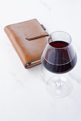 茶色の革のシステム手帳と赤ワインのグラス
