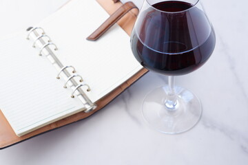 リング式のシステム手帳と赤ワインのグラス
