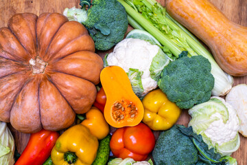 Various vegetables are laid out on a wooden table. Large assortment of vegetables food. pumpkin...