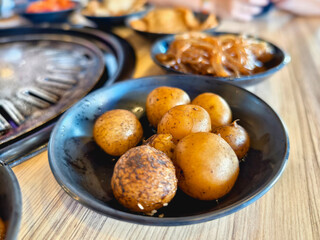 Close-up of seasoned potatoes served at a samgyupsal Korean BBQ restaurant, complemented by traditional banchan side dishes.