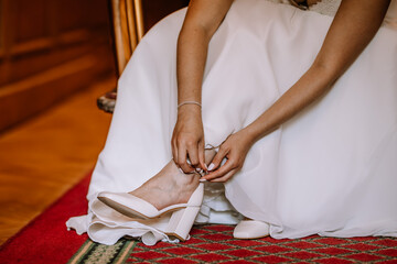 Valmiera, Latvia - August 19, 2023 - Close-up of a bride sitting down, buckling her white wedding...