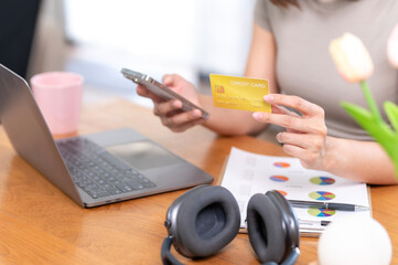 Fototapeta premium A woman is holding a credit card and a cell phone