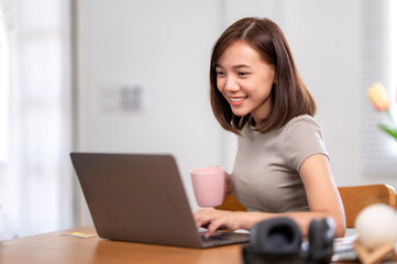 Fototapeta premium A woman is sitting at a table with a laptop and a pink cup