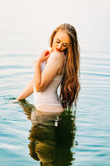 Beautiful Caucasian female in white lingerie standing in river
