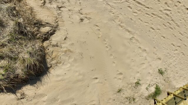 Direct aerial showing the sand, dunes, and stair access point.