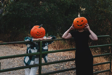Two friends wearing carved Halloween pumpkin heads