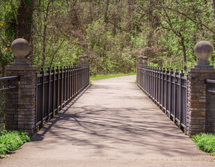 A concrete pathway with iron railings over a creek