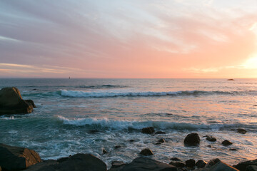 Sunset paints the sea and rocks in warm, tranquil tones