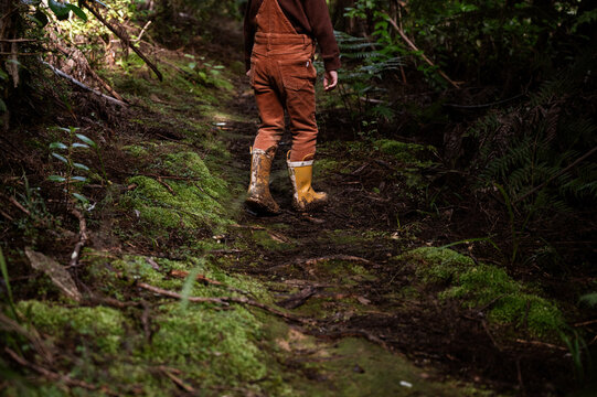 Cropped view of child walking in forest with muddy yellow boots