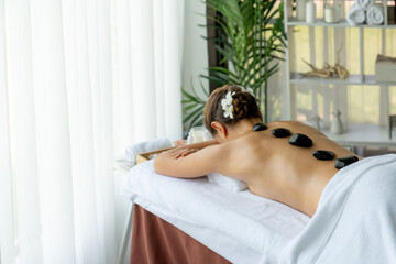 Hot stone massage at spa salon in luxury resort with day light serenity ambient, blissful woman...
