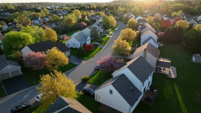 Dramatic light, aerial turn reveals American neighborhood, residential development community during spring season magic hour, Small Town America