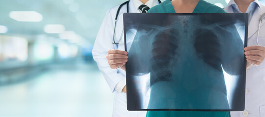 Radiologist and Doctor team look at x-ray image of human chest and lungs at hospital backgroud wide view.