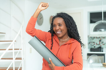 Excited black woman with yoga mat ready for class at gym
