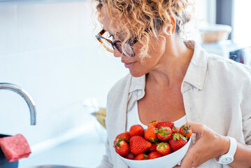 One midage woman at home with fresh bowl of red strawberries seasonal fruit. Concept of weight loss...