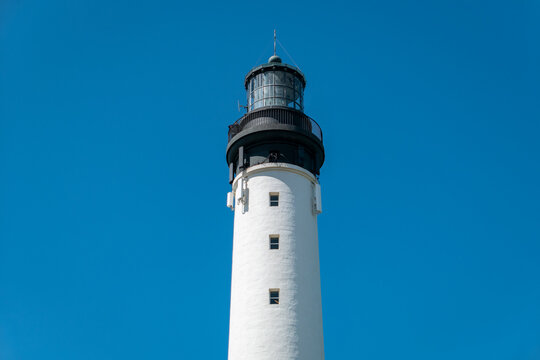 Farol com antenas de comunica&ccedil;&otilde;es no alto da torre com um c&eacute;u azul como fundo