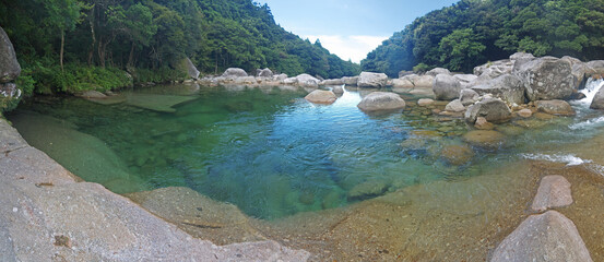 Yakushima nature scenery with Mountain river stone riverbank and small natural pond with big...