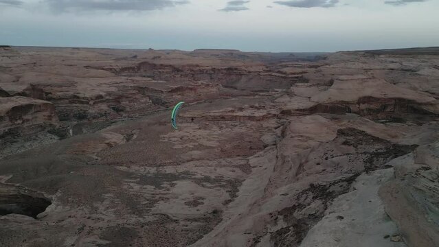 Paraglider With Colorful Chute Flying Over Canyons In Utah, USA. tracking shot