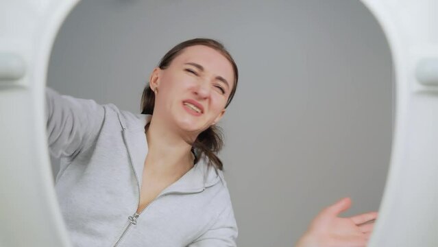 Mom and son look into toilet, grimace, cover their noses from unpleasant smell and feel nauseated by what they see. View from toilet bottom. Cleanliness and hygiene concept