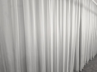 Obraz premium the curtain hangs from the ceiling to the floor. smooth satin synthetic curtain dividing the space and forming a soft textile background. weights at the bottom of the edge of the fabric