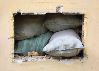 A gap in the yellow wall littered with sandbags