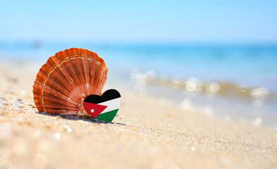 Sandy beach in Jordan. Jordan flag in the shape of a heart and a large shell. A wonderful seaside...