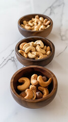 Fototapeta premium Three wooden bowls filled with cashews neatly arranged on a marble counter