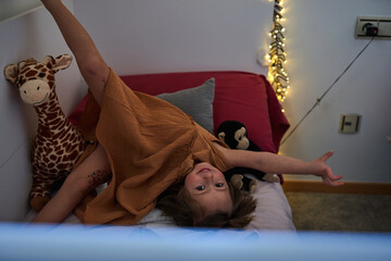 A small girl having fun in her bedroom.